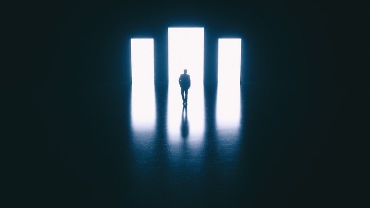 Photo By Adam Jícha, Shows A Man Walking Toward Three White Rectangles From A Dark Room