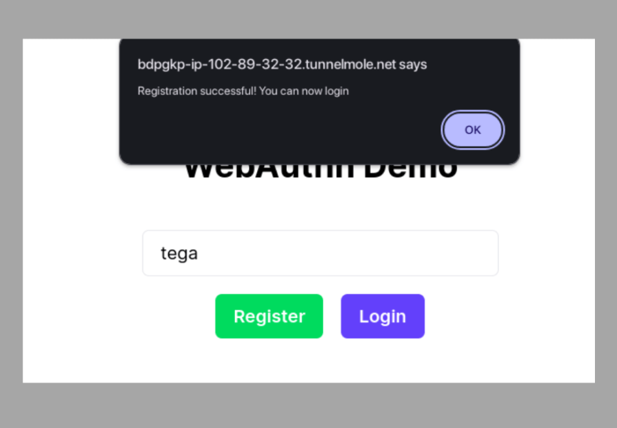 Screenshot of a WebAuthn demo interface showing a registration success popup. The popup, from a Tunnelmole URL, displays the message ‘Registration successful! You can now login’ with an ‘OK’ button. The WebAuthn demo form is visible in the background with the username ‘tega’ entered in the input field and ‘Register’ and ‘Login’ buttons below it.